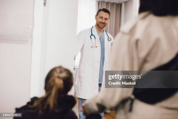 smiling male doctor looking at female patient in medical clinic - allmänläkare bildbanksfoton och bilder