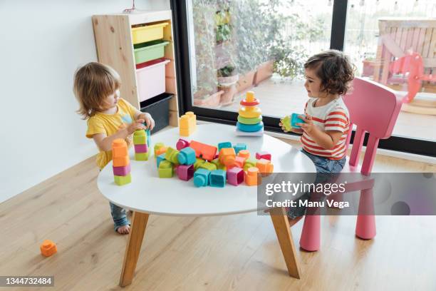 high angle side view of adorable little kids playing with colorful educational toys and blocks at table in modern playroom - modern baby nursery stock pictures, royalty-free photos & images