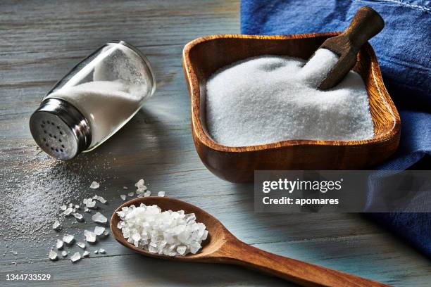holzschüssel gefüllt mit grobkörnigem meersalz auf rustikalem hintergrund - sodium stock-fotos und bilder