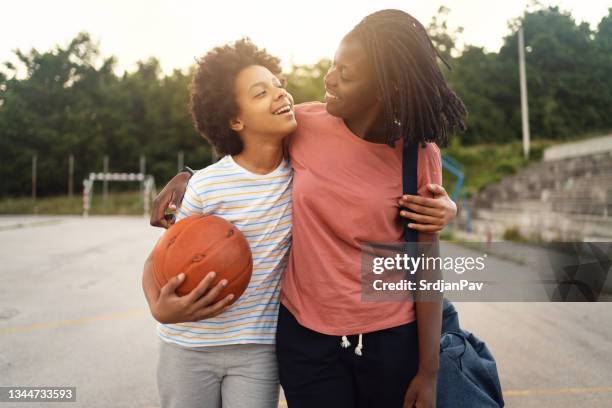 mãe orgulhosa da etnia negra, pegando sua filha adolescente de sua prática de basquete - família monoparental - fotografias e filmes do acervo