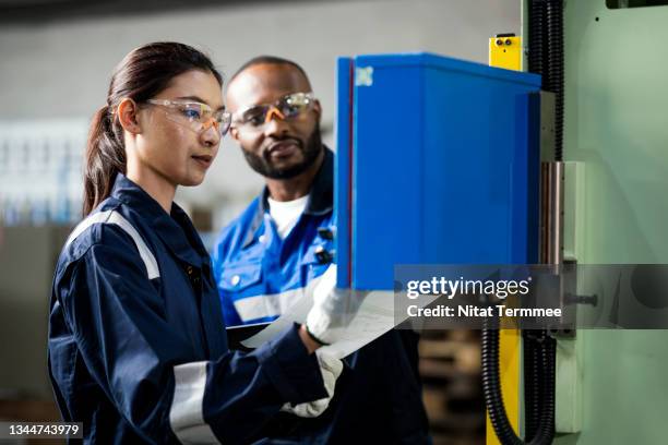 senior industrial engineering explaining a basic working process on the switchboard of the automated press machine to junior technicians in a production line. communication, collaboration, and change management in manufacturing industry. - manual worker milling machine operator photos et images de collection