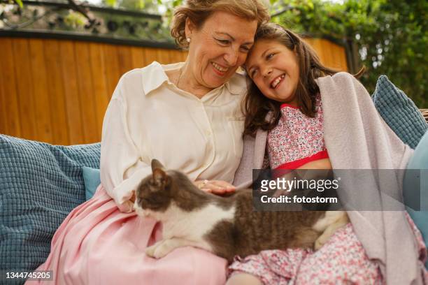 großmutter und enkelin kuscheln draußen mit ihrer katze - old woman cat stock-fotos und bilder