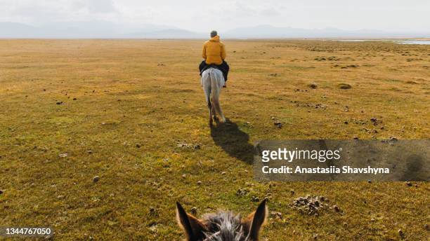 man traveler riding a horse at the mountain lake song kul in kyrgyzstan - yurt stock pictures, royalty-free photos & images