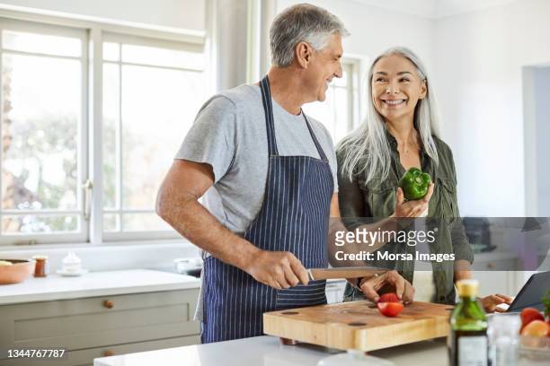 smiling woman with man preparing food at home - healthy older couple stockfoto's en -beelden