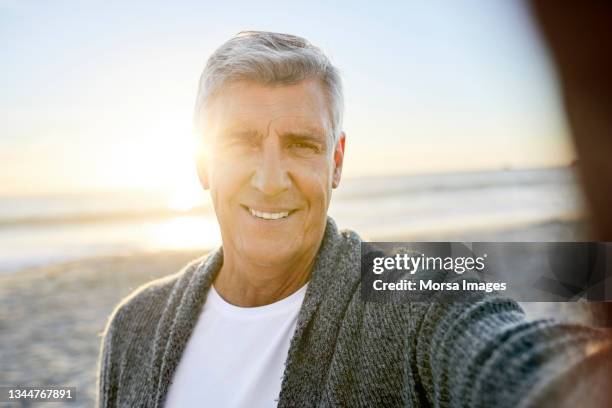 nahaufnahme eines lächelnden mannes, der selfie am strand macht - männer portrait gesicht close up stock-fotos und bilder