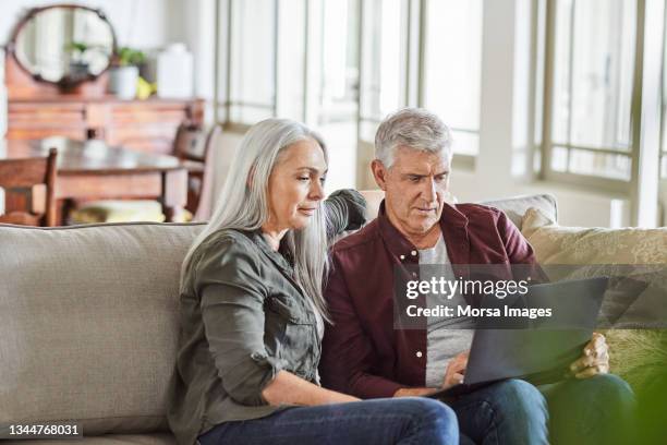 reifes paar mit laptop auf sofa zu hause - couple 50 55 laptop stock-fotos und bilder