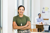Soldier with arms crossed smiles for camera in workplace