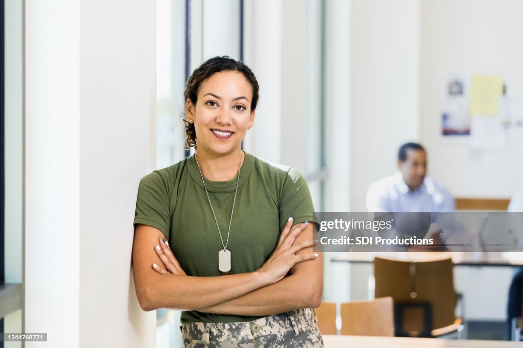 Soldier with arms crossed smiles for camera in workplace
