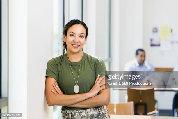 soldier with arms crossed smiles for camera in workplace - african american soldier bildbanksfoton och bilder
