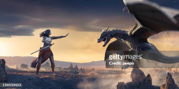 un dragon dans les airs avec la bouche ouverte volant près d’une femme chevalier debout avec la main ouverte. - dragon photos et images de collection
