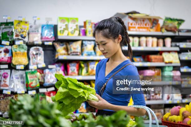selects vegetables at a supermarket - groenteboer stockfoto's en -beelden