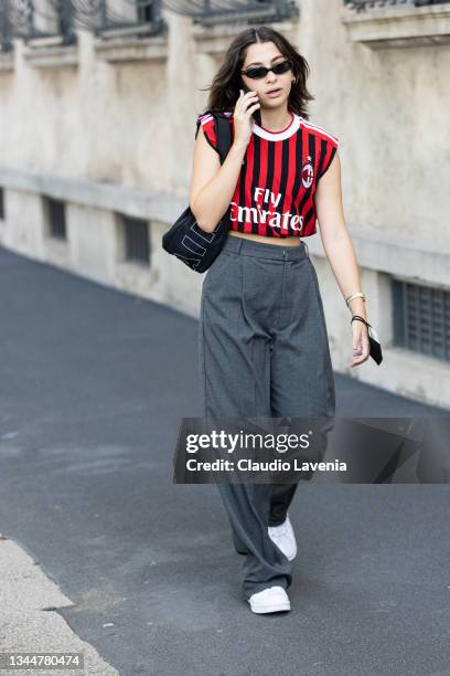 Guest, wearing an AC Milan shirt and grey pants, poses ahead of the Prada fashion show during the Milan Fashion Week - Spring / Summer 2022 on...