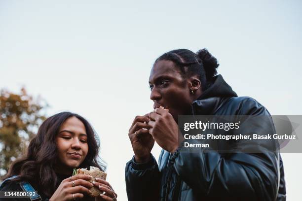 two friends eating sandwiches - black man eating stock pictures, royalty-free photos & images