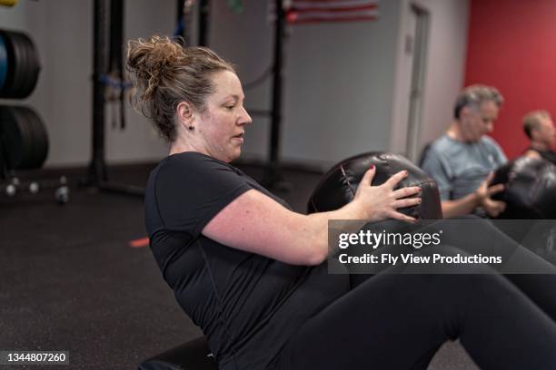 woman doing abdominal workout in group fitness class - ordinary guy stock pictures, royalty-free photos & images