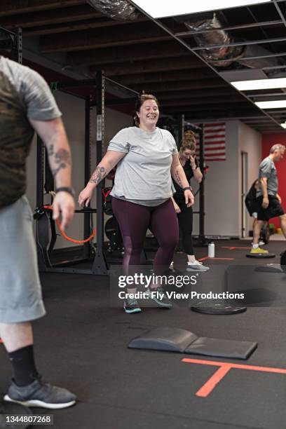 happy and confident woman attending a group fitness class at the gym - cardiovasculaire training stockfoto's en -beelden