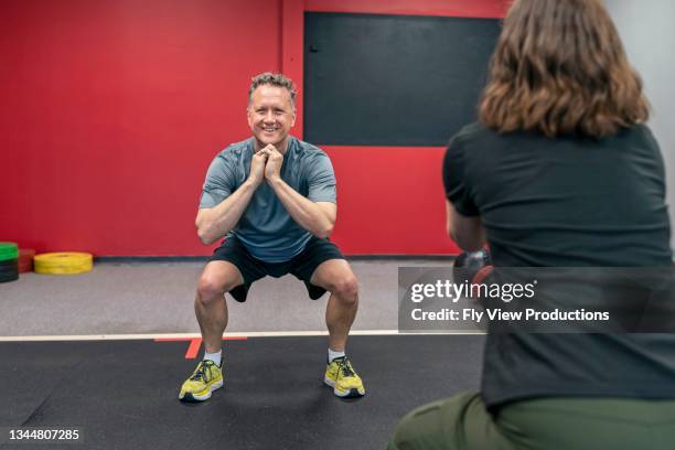 mature man exercising with personal trainer - boutique gym stock pictures, royalty-free photos & images