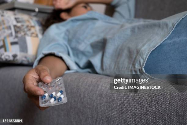 sad and depressed woman lying on the sofa with a pill tablet - yellow september stock pictures, royalty-free photos & images