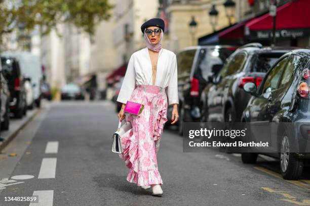 Salome Chaboki wears a black wool / felt beret hat, black sunglasses, a pale pink scarf, a white oversized sleeves / V-neck body jumpsuit, a pink...