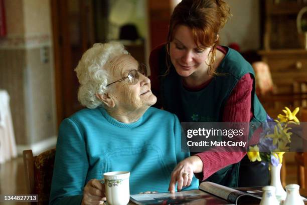 Elderly woman and her carer looks at a magazine in a residential care home in Bath, on March 21, 2006 in Somerset, England. As people live longer and...
