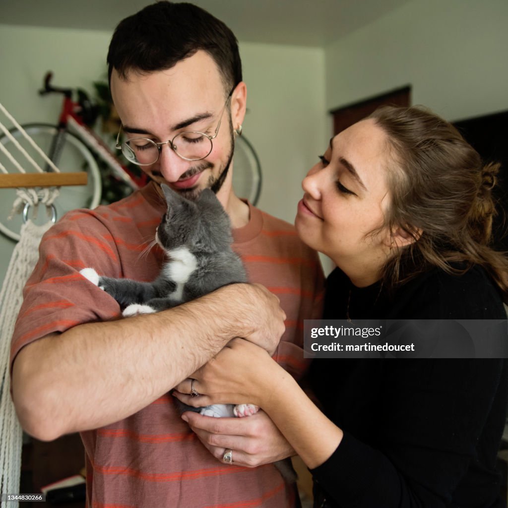 Retrato de la pareja millennial y el gatito recién adoptado en casa.