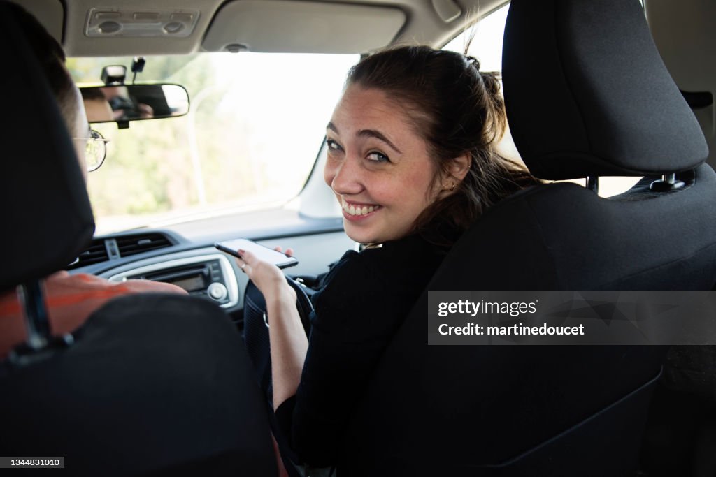 Millennial woman and newly adopted kitten in pet carrier in car.