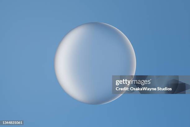 single large glass bubble against blue background - sfeer stockfoto's en -beelden