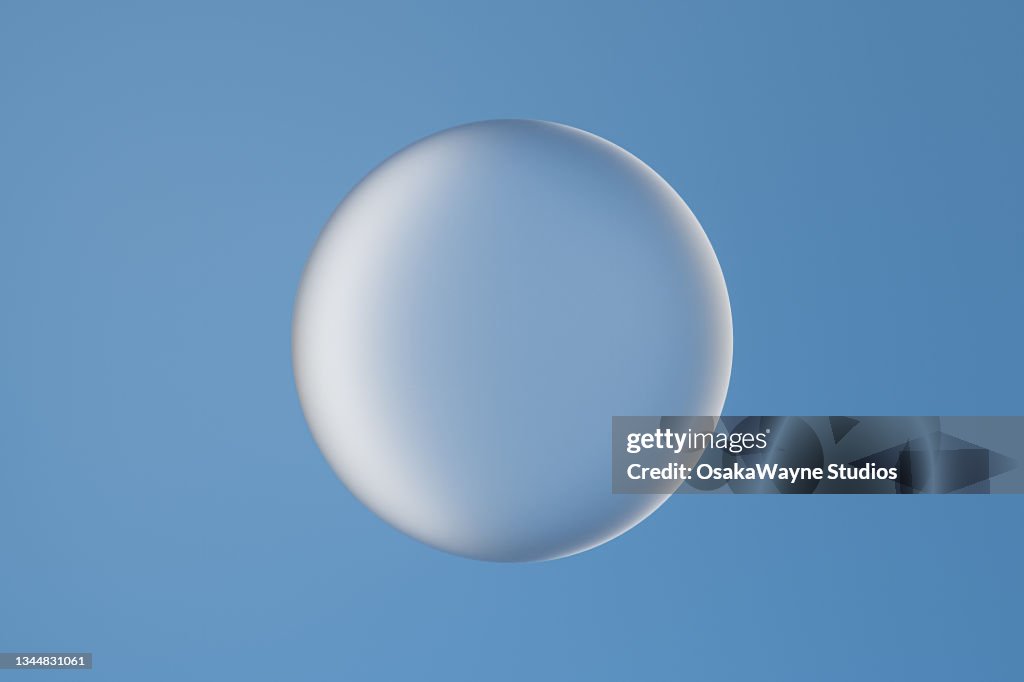 Single large glass bubble against blue background