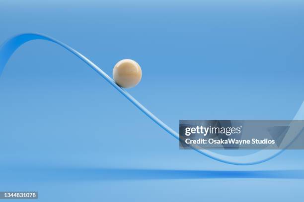 glossy white ceramic ball moving along oscillating curve - laufbahn stock-fotos und bilder