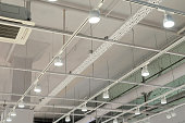 Ceiling with bright lights in a modern warehouse, shopping center building, office or other commercial real estate object. Directional LED lights on rails under the ceiling