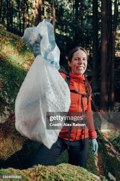 a volunteer participating in a recycle drive proudly holds a bag full of trash in wilderness area - full responsibility stock pictures, royalty-free photos & images