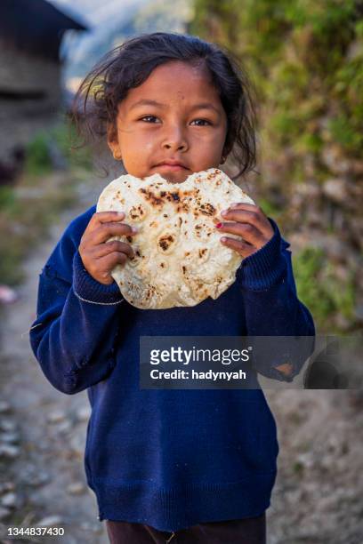 nepali little girl eating chapatti, flat bread in village near annapurna range - roti stock pictures, royalty-free photos & images
