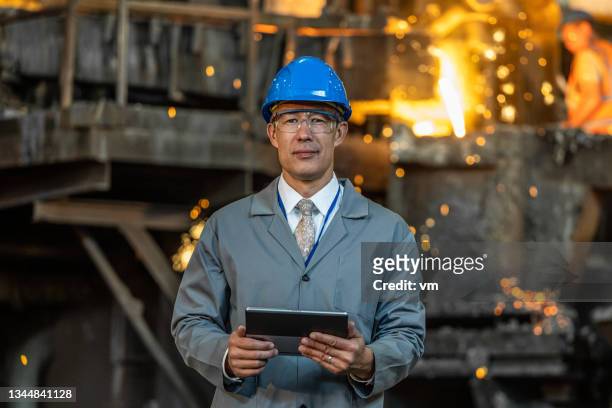 man standing in metallurgy plant and looking at camera - steel plant stock pictures, royalty-free photos & images
