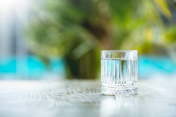 clean water in small glass on table - drink-glasses-on-table stock pictures, royalty-free photos & images