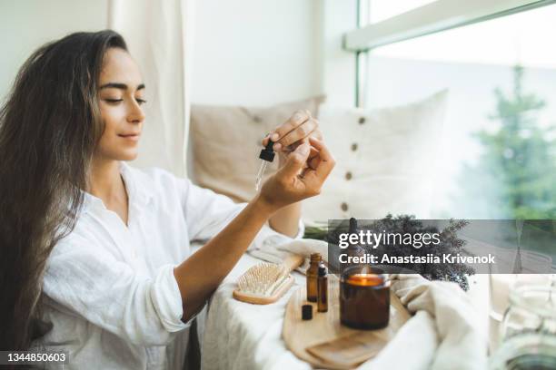 woman with long hair using serum for hair loss treatment. - scented candle stock pictures, royalty-free photos & images