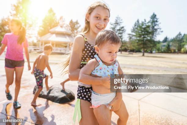 sisters playing at the splash park - baby at splash pad stock pictures, royalty-free photos & images