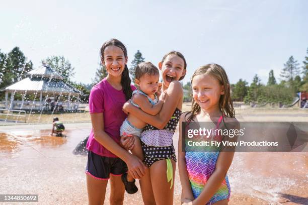 happy group of girl cousins playing at the water park - cousins stockfoto's en -beelden