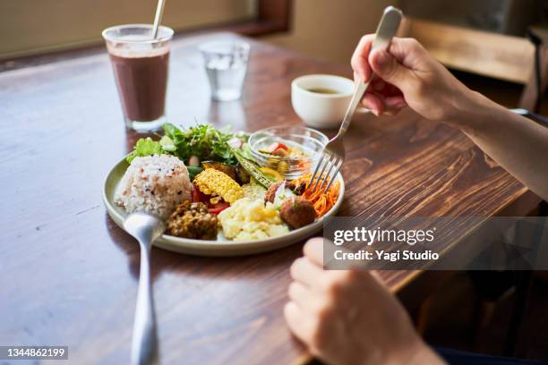 japanese woman eating a vegan lunch at a vegan cafe - 皿　和 ストックフォトと画像