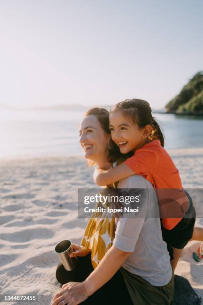 young girl hugging her mother from behind on beach at sunset, japan - free six photo stock pictures, royalty-free photos & images