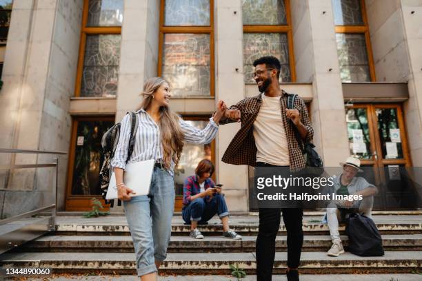 low angle view of happy young university students greeting outdoors in front of campus. back to university concept. - college campus students stock-fotos und bilder