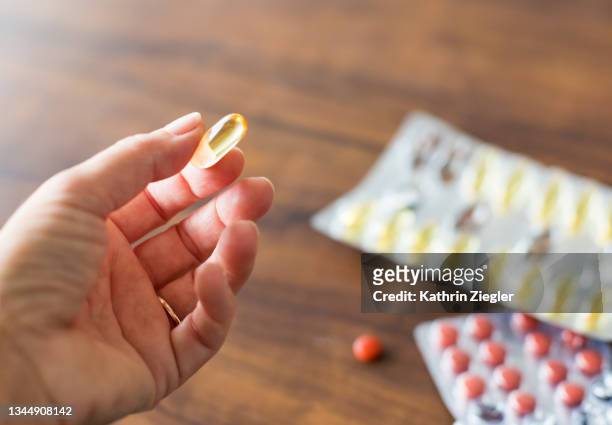 woman holding yellow omega-3 nutritional supplement capsule, close-up of hand - fish oil ストックフォトと画像
