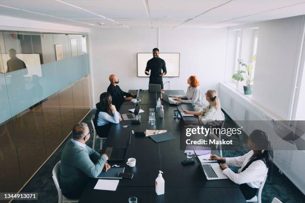 high angle view of businessman giving presentation colleagues in board room at office - presenting ストックフォトと画像