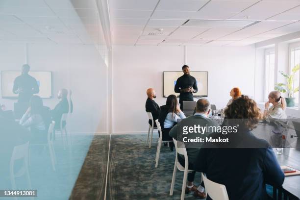 businessman sharing business ideas with male and female colleagues in office - social distancing meeting stock pictures, royalty-free photos & images
