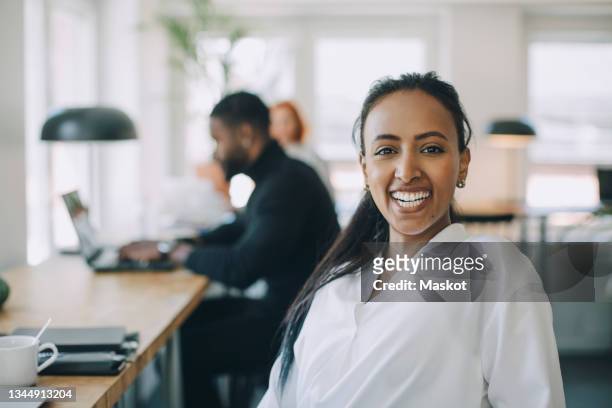 portrait of happy businesswoman in co-working space - personas en el fondo fotografías e imágenes de stock