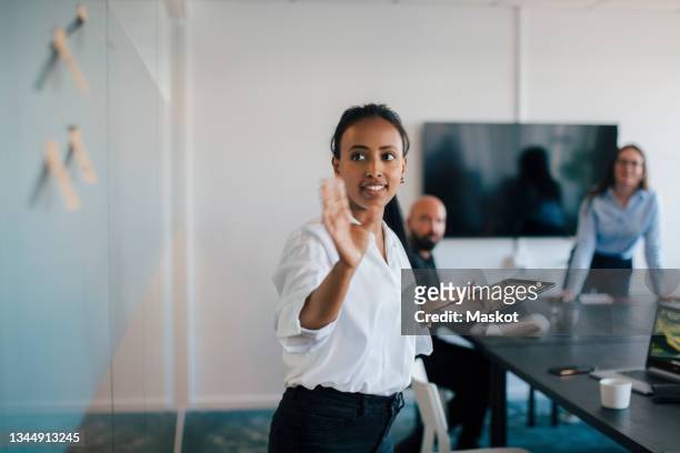 businesswoman brainstorming over adhesive notes in meeting at board room - board room stock-fotos und bilder