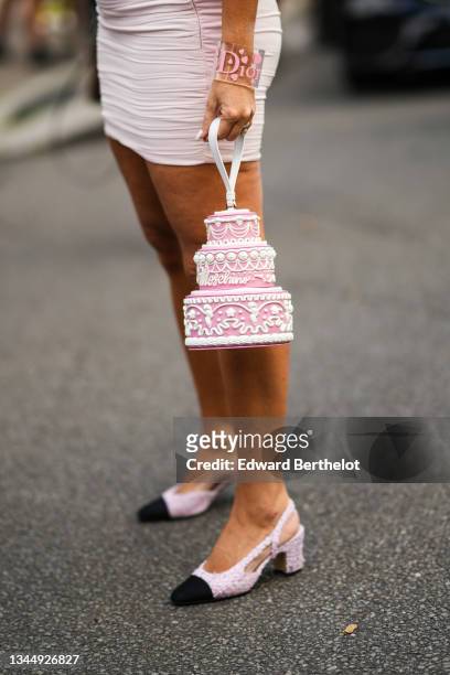 Guest wears a pale pink ruffled tube short skirt, a transparent with pink pattern large bracelet from Dior, a pink and white handbag in the shape of...
