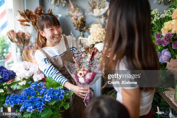 florist helping a customer - japanese flower arrangement stock pictures, royalty-free photos & images