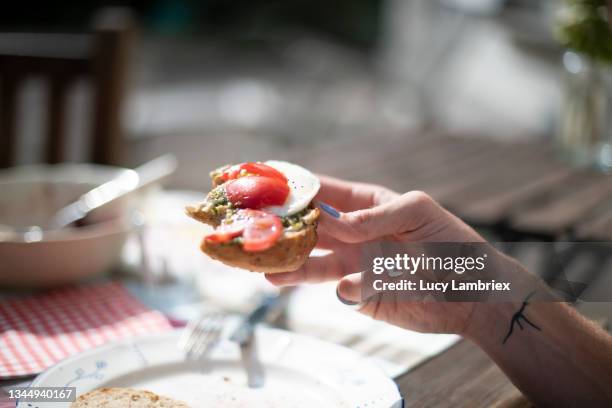 non-binary person eating a caprese sandwich - pesto stock-fotos und bilder