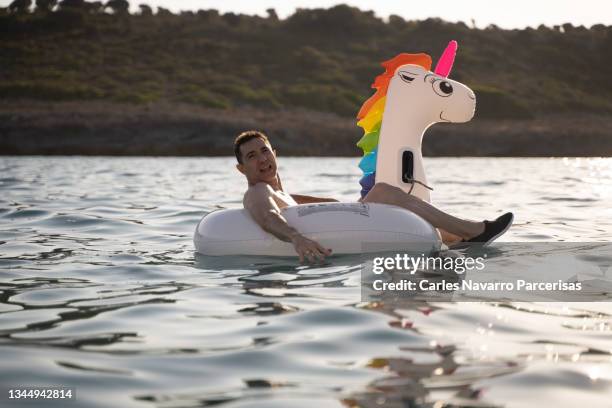 adult man floating in the sea with a unicorn-shaped float - bronzage humour photos et images de collection