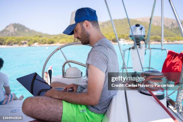 profile of a man sitting in the deck of a sail boat working with a laptop - profile laptop sitting stock pictures, royalty-free photos & images