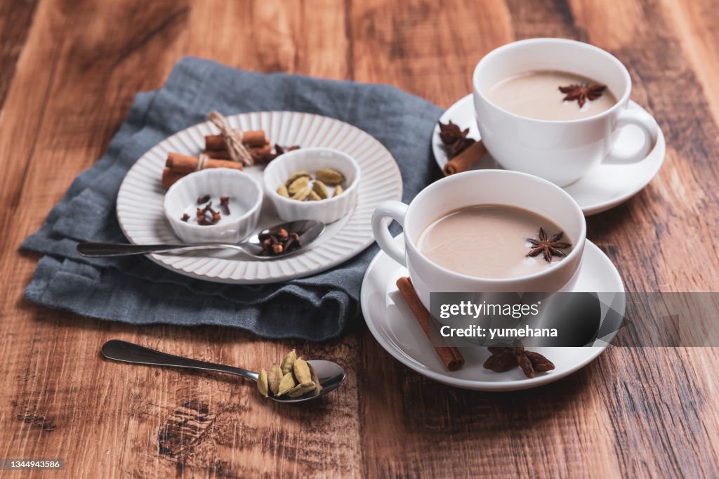 Té indio masala chai. Té especiado con leche sobre la mesa rústica de madera.
